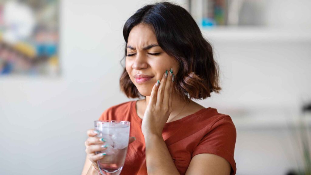 Woman experiencing tooth sensitivity while drinking water